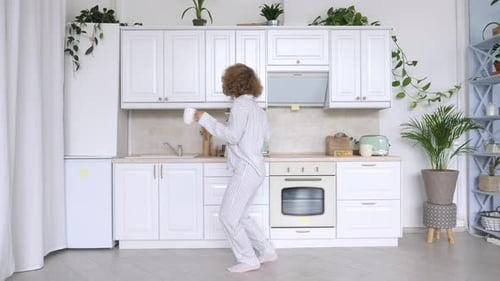 Woman Dances in Bright Kitchen in Pajamas