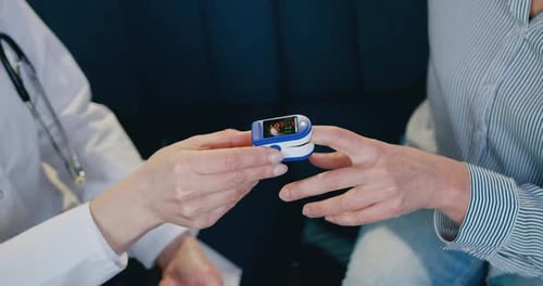 Doctor Using Oximeter on Patient's Finger