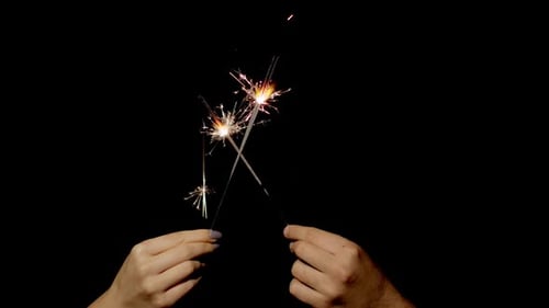Hands Holding Sparklers on Black Background
