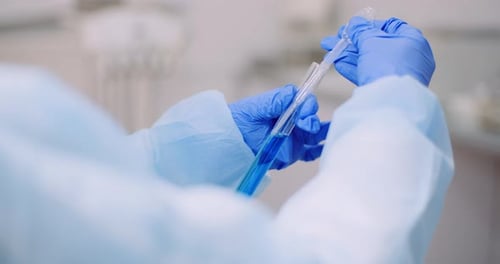 Lab Technician Pipetting Blue Liquid into Test Tube