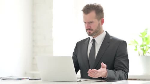 Frustrated Man Working on Laptop at Desk