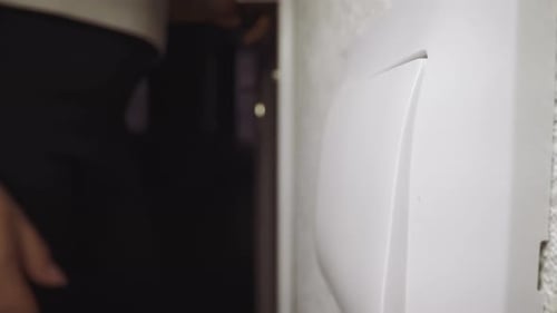 Mulher pressiona a tecla do interruptor para acender a luz que entra na sala