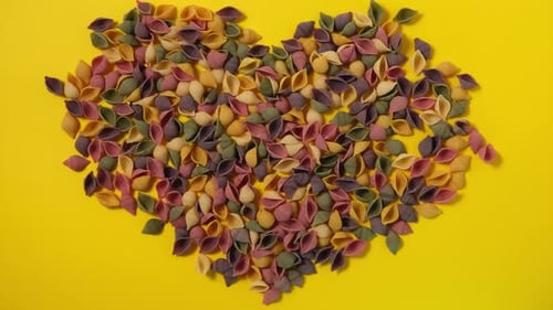Colorful Pasta Shells Arranged on Yellow Background