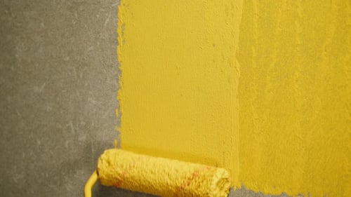 Yellow Paint Roller Applying Fresh Coat to Wall