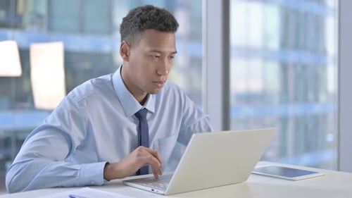 Afroamerikanischer Geschäftsmann wird bei der Arbeit am Laptop schockiert