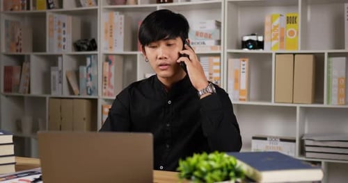 Young Man Talking on Smartphone at Desk
