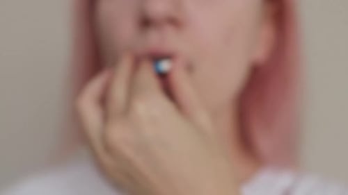 Young Woman Taking Blue and White Capsule Pill