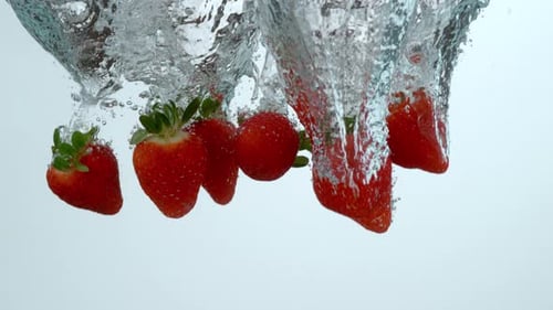 Bright Red Strawberries Dropping Into Clear Water