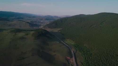 AERIAL, TOP DOWN: Dark Colored Car Driving Down an Asphalt Road Crossing the Vast Forest on a Sunny