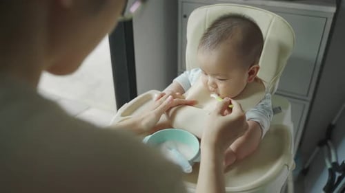 Adult Feeds Cute Infant at Home