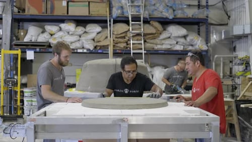 Workers measuring circular mold on table in workshop