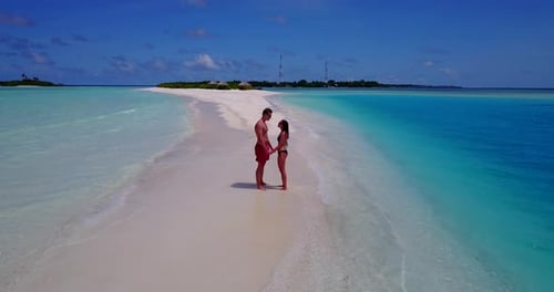 Hombre y mujer felices en una romántica luna de miel disfrutan del lujo en la playa sobre un fondo 4K de arena blanca y limpia