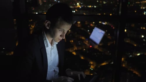 Man Working on Laptop Overlooking City at Night