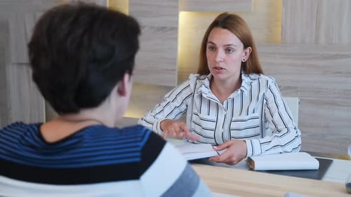 Junge Geschäftsfrau chattet mit Praktikantin und diskutiert Kollegen im Vorstellungsgespräch