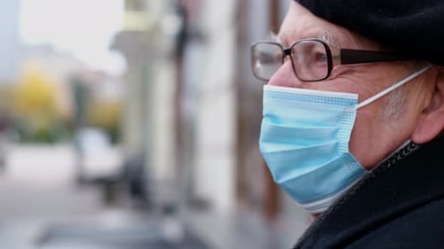 Portrait of a Sad Old Man with a Blue Mask and Beret Sitting in a City Park