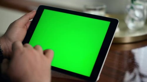 Adult Hand Swiping Green Tablet Screen Closeup