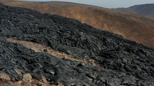 Slide and Pan Footage of Wide Lava Stream Dark Volcanic Material with Rough and Rugged Surface
