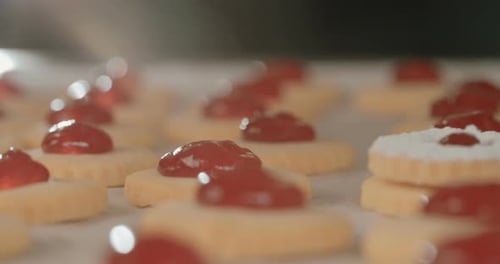 Bäcker bereitet Butterkekse mit Erdbeermarmelade und Puderzucker