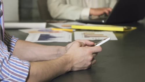 Gros plan recadré d'un homme d'affaires tapant sur son téléphone intelligent au bureau