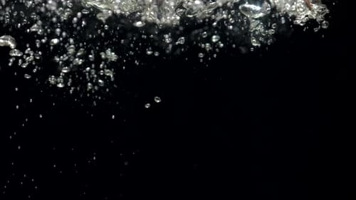 Luftblasen in Zeitlupe im Wasser, die auf schwarzem Hintergrund an die Oberfläche steigen