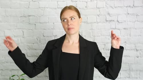 Woman Explaining with Hand Gestures Against Brick Wall
