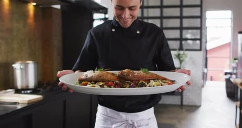 Smiling Chef Presents Fresh Fish Dish in Kitchen