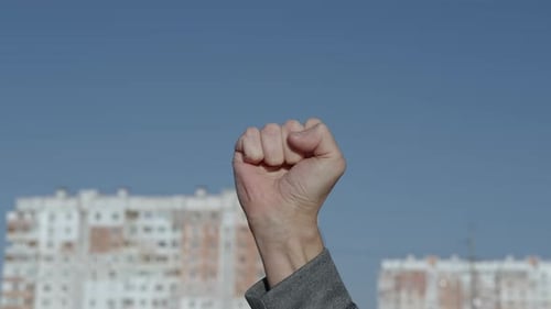 Man Clenching Fist in Front of Buildings
