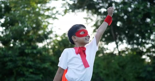 Un garçon héros en rouge a du pouvoir dans le jardin