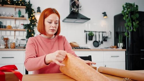 Woman Wraps Gift in Kitchen for Christmas Holiday