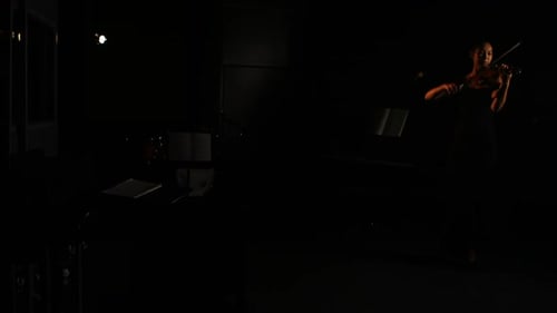 Woman Playing Violin in Dark Studio