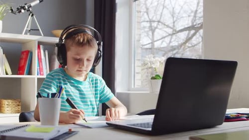 Boy Studying with Laptop and Headphones at Home