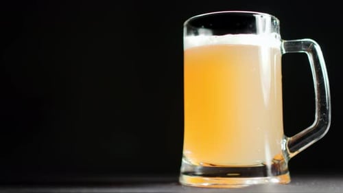 Desempenho de refrescar e apetitosa bebida de malte frio em caneca com espuma macia, rotação lenta