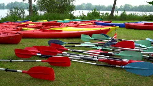 Colorful Kayaks and Paddles by a Calm Lake