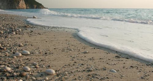 Soft Calm Foam Waves Rolling Ashore on Sandy Beach of Mediterranean Sea in Golden Sunset Evening Sun
