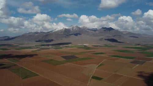 Drohnenblick über Ackerland gegen verschneiten Berg