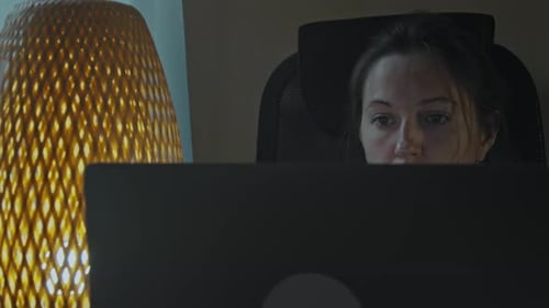 Woman looks at a computer screen at night