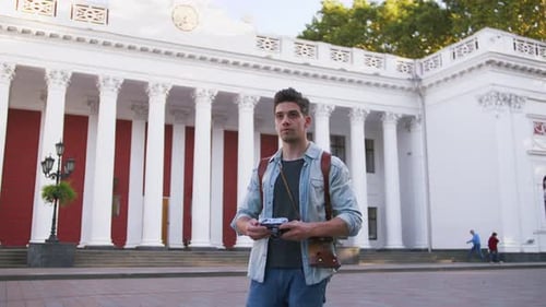 Young Attractive Handsome Man Tourist with Backpack Taking Photos on Vintage Camera in Old City