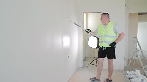 Der Bauunternehmer malt die Wände mit einer Walze weiß