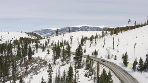 Grauer LKW, der entlang der Bergstraße fährt, Winter, Schnee, Luftaufnahme,