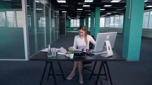 Faire des heures supplémentaires Une jeune femme d'affaires est assise à un bureau dans le bureau et travaille sur un Pc Manager travaille sur