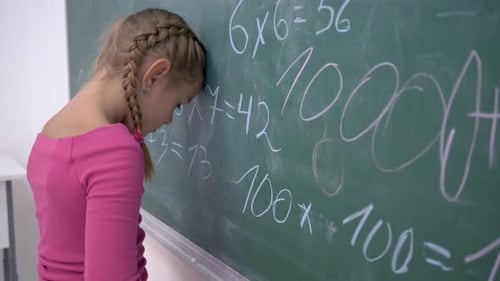 Frustrated Child Leans Against Classroom Chalkboard