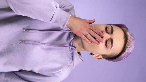 Jeune femme adulte verticale bâillant frémissant sur fond violet