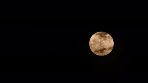 Glowing Full Moon Behind Wispy Clouds at Night
