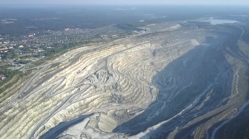 Vol aérien au-dessus d'une immense fosse d'amiante par une ville moderne