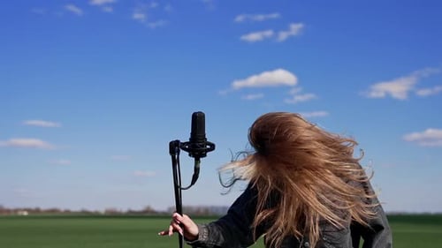 Woman Singing into Microphone in Field Outdoors