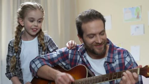 Girl Sings with Man Playing Guitar at Home