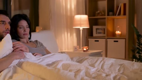 Couple Watching Frightening Movie in Bed at Night
