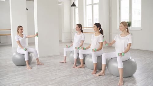 Pregnant Women Exercising with Dumbbells in Bright Studio