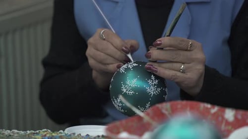 Hands Decorating Christmas Ornament with Snowflakes