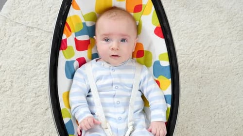 Adorable Baby Lying in Bouncer on Carpet